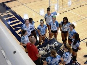 Jacksonville volleyball coach David Clark (red shirt) gathers his team during its final practice before opening the season Thursday night.