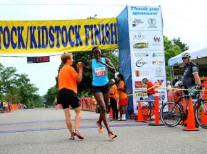 Marion Kandie is greeted after crossing the finish line as the woman's winner in Saturday's Woodstock 5K. In the cover photo, Patrick Cheptoek wins his third straight Woodstock. (Photos by Greg McWilliams) In the upper photo, Cheptoek wins his third straight Woodstock (Photo by Al Muskewitz) (Click on photos to enlarge)