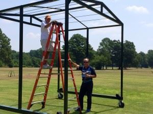 Jim Prince (on ladder) and Cane Creek director of golf operations Kenny Szuch work on a moveable cover that will become a fixture on course's range. 