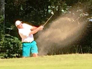 Gary Wigington (top) blasts out of a bunker during the second round of the Calhoun County Championship Saturday at Cane Creek. Below, Jeremy McGatha follows the flight of his approach shot into the 10th green.