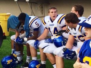 Piedmont junior defensive back Deven Hincy fills in his teammates on the details of his second-quarter interception. Below, on a hot day, manager Weston Kirk goes extra hard for his team.