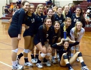 The Donoho volleyball team poses with the trophy after winning the Silver Bracket of its tournament Saturday. In the cover photo, Camille Fink (7) and Madison Gaines strike a pose at the net. 