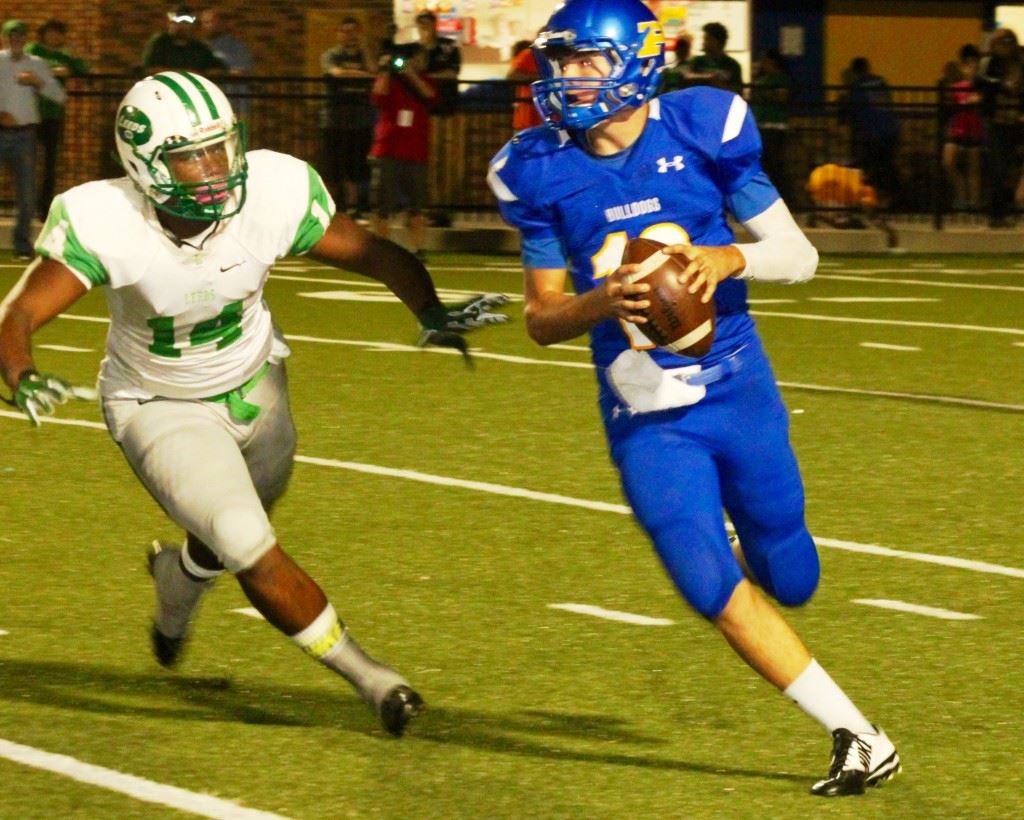 Piedmont quarterback Tyler Lusk (R) rolls out to avoid the pressure of Leeds' Javier Burrows. In the cover photo, Leeds' quarterback Tadarryl Marshall accounted for four Green Wave touchdowns Thursday night. (Photos Special to East Alabama Sports Today)