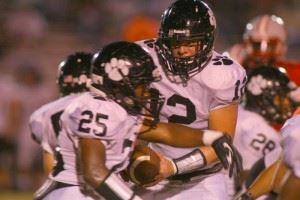 Wellborn quarterback Landon Machristie hands off to Derrick Rhoden (25) in the Saks game. In the cover photo, Panthers coach Jeff Smith discusses strategy with an assistant. (Photos by Greg McWilliams)