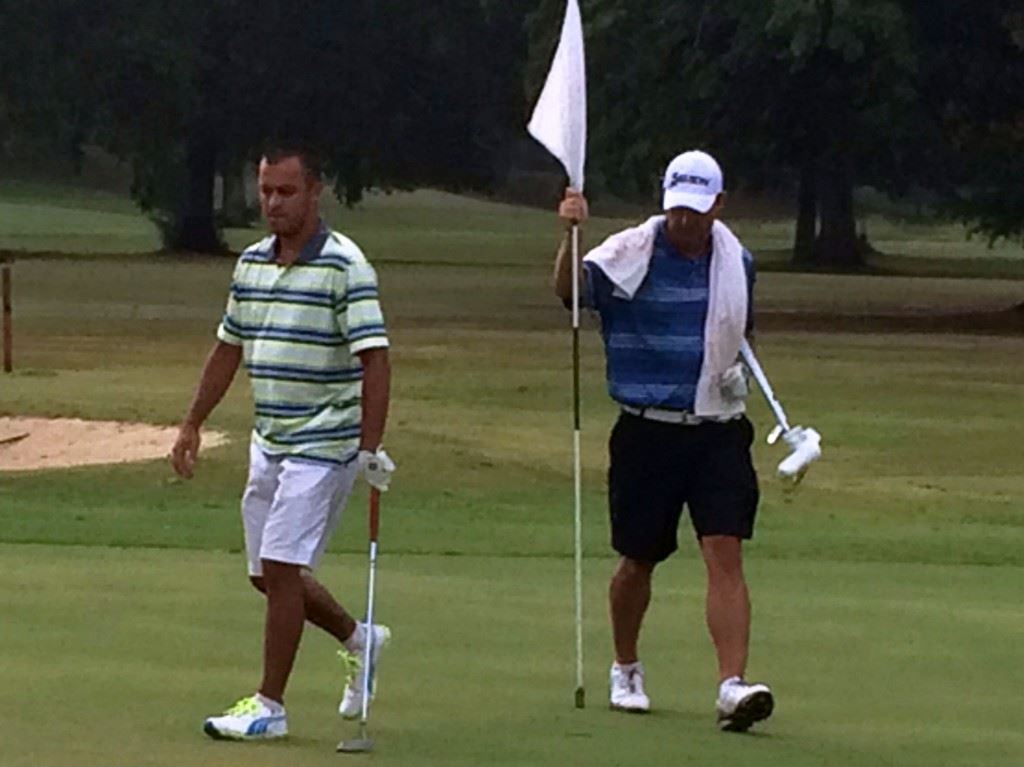 Jaylon Ellison (R) returns the flagstick to the cup after winning the third hole in his match with Billy Thompson.