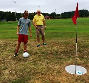 Pete Eschrig (R) helps Oxford's Grant Biehunko line up a FootGolf "putt" during Saturday's introduction. In the main photo, Eschrig pulls out a few birdies with FootGolfers (from left) Wilmer Alvarez, Ray Alvarado and Jose Alvarez.