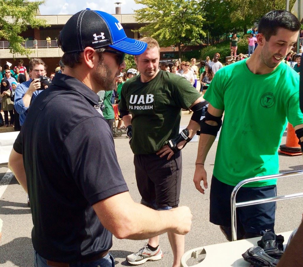 Sprint Cup driver Jimmie Johnson inspects one of the gurneys in the UAB Homecoming Gurney Derby Wednesday. In the cover photo, he arrives in the Talladega pace car. Below, he drops the green flag to start one of the Derby races.