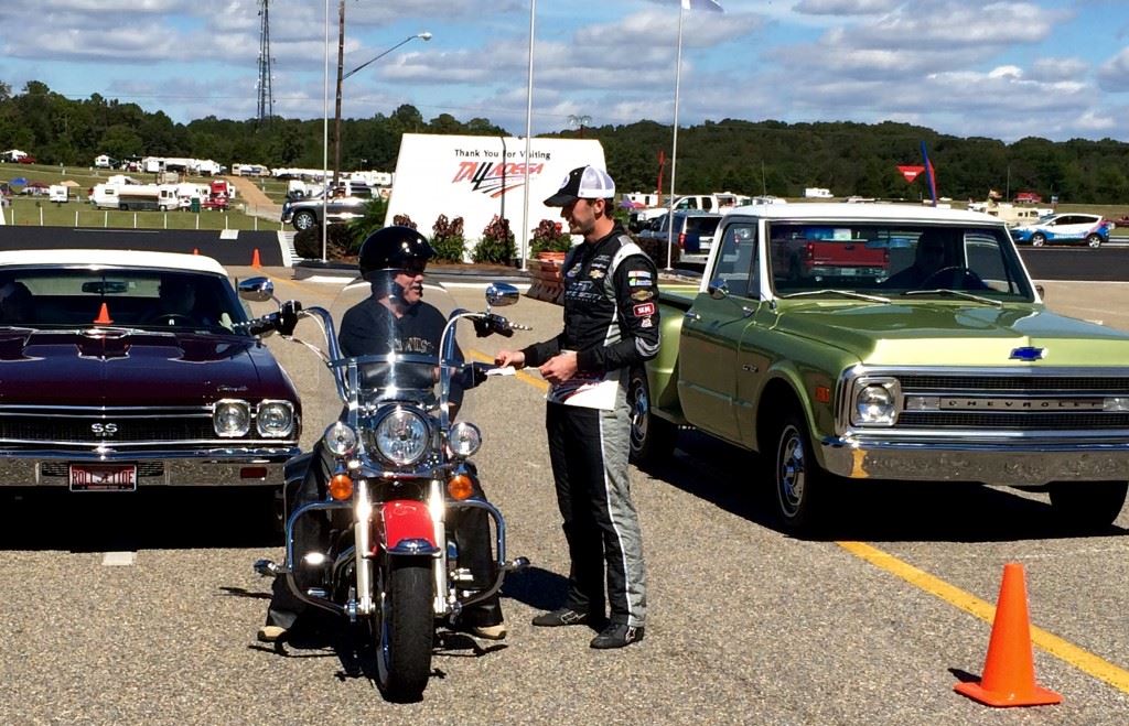 Truck racer Ben Kennedy (R) hands some race tickets to Mack Huckaby in Thursday's recreation of an iconic picture of Kennedy's great grandfather Bill France Sr. selling tickets (on cover) at Talladega's main gate 45 years ago.