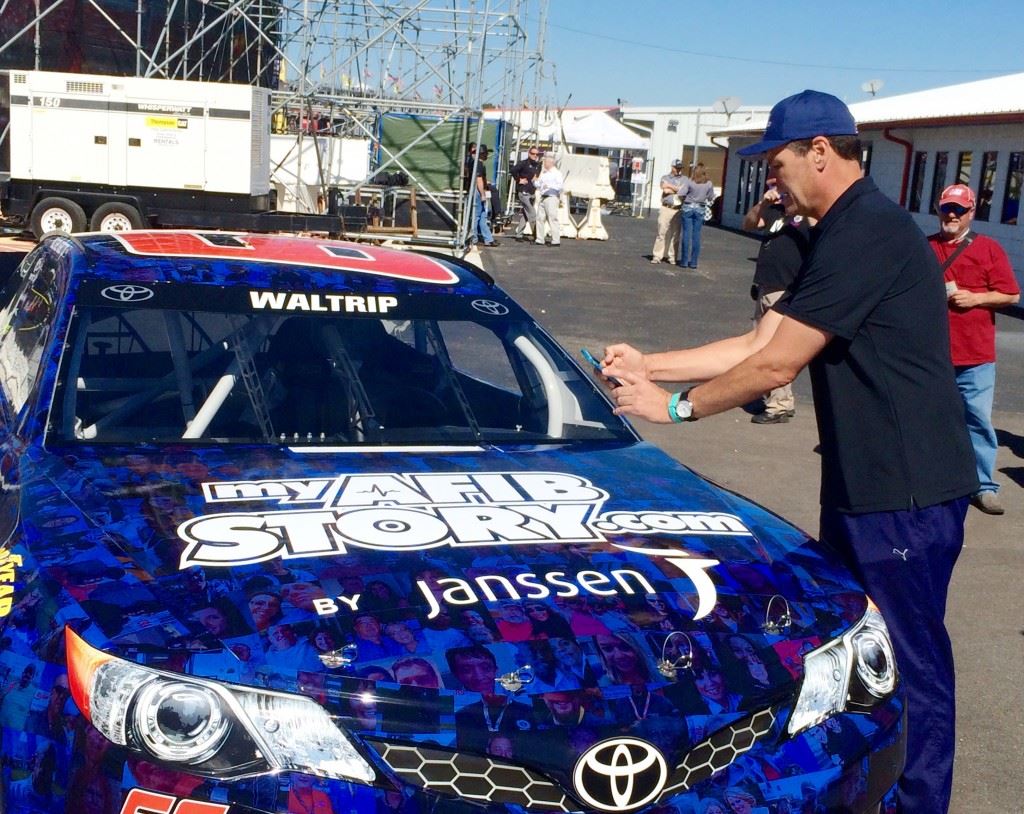 Michael Waltrip takes pictures of people he recognizes among the 3,000 faces in the paint scheme of the Sprint Cup car he'll drive in Sunday's GEICO 500. Among those were his Dancing With The Stars partner Emma Slater and a couple Dale Earnhardt fans. During the walk-around he kept asking, 'Where's Alfonso?" a reference to DWTS competitor Alfonso Ribiero.