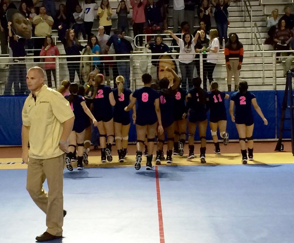 Jacksonville coach David Clark returns to the bench as his players rush to salute their fans after advancing to the Class 4A state championship match.