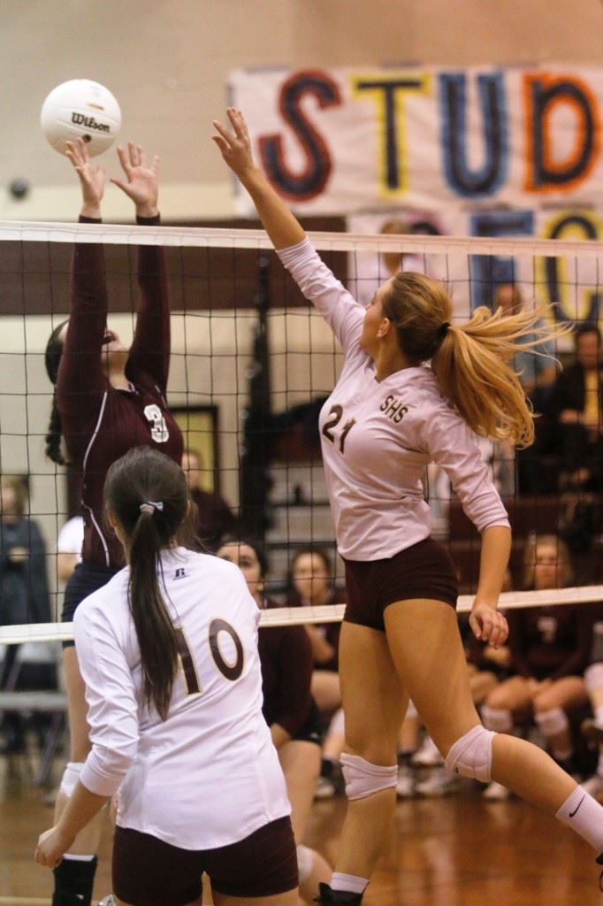 Sacred Heart's Olivia Simmons (21) sends one of her 20 block attempts over the outstretched hands of Donoho's Hannah Christian (3) during Monday's area title match. (Photo courtesy of Kristen Stringer/Krisp Pics Photography)