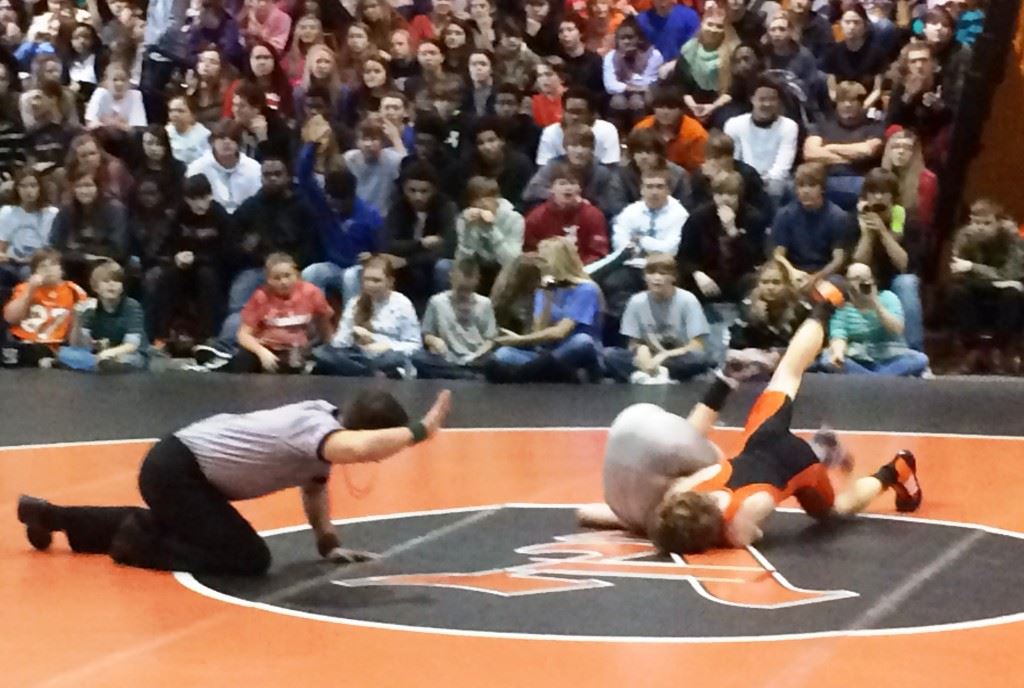 Alexandria's Fletcher Swindall is moments from pinning Piedmont's Solomon Doss to open the Valley Cubs' groundbreaking 57-24 victory. On the cover, Alexandria coach Frank Hartzog (center) and Piedmont's Harley Lamey (left) go over their lineups.