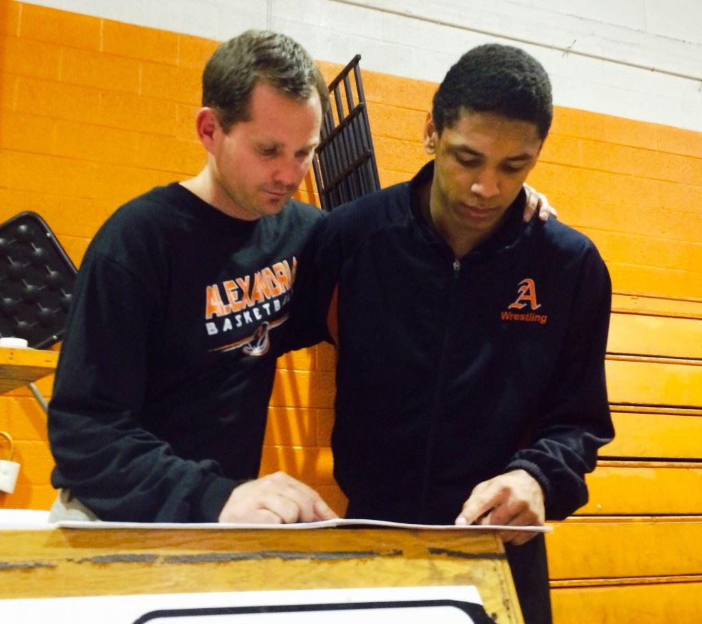 Alexandria eighth-grader Christian Knop (R) and coach Frank Hartzog review the results of Thursday night's matches. Knop went 3-0 at 160 to become the first wrestler in school history to win 50 times in a season.