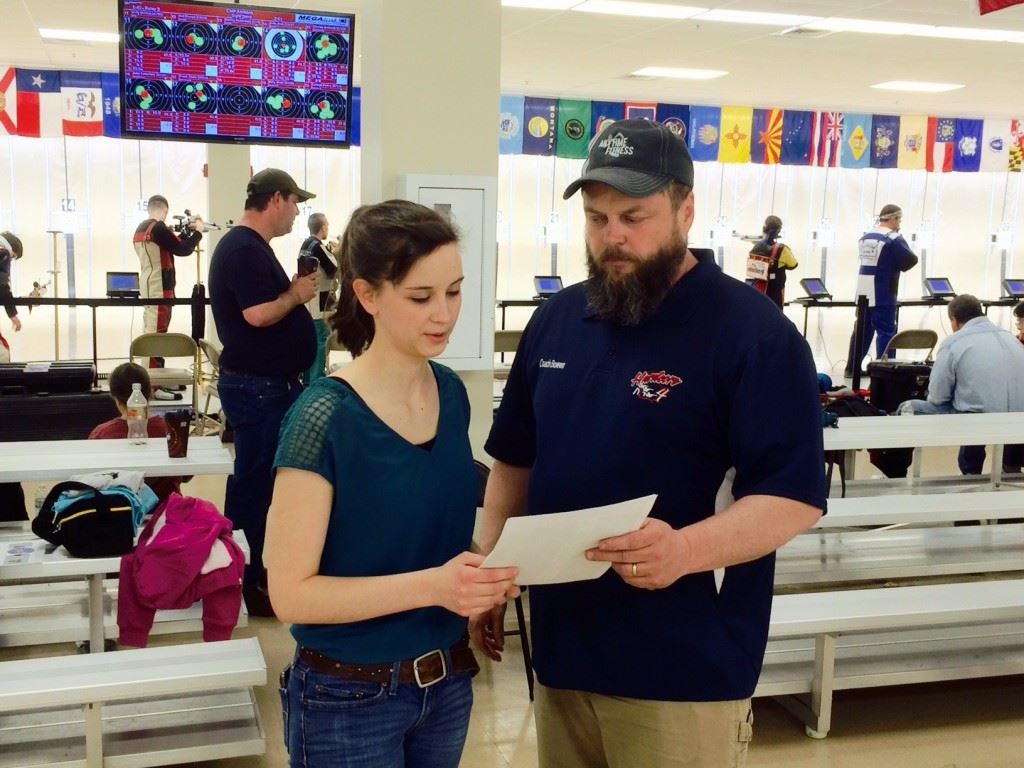 Rachel Kimbell reviews her results with coach Al Bowen after winning the air rifle competition at the Dixie Challenge. On the cover, Enterprise's Cori Horton shoots from the standing position. 