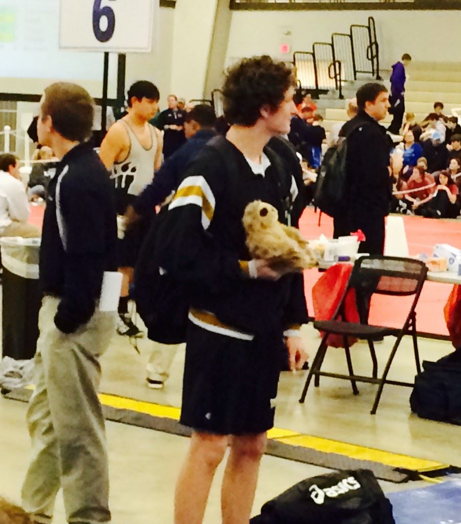 Oxford freshman Matt King watches the action on another mat while holding the Yellow Jackets' 'game sloth.' The Jackets have used the furry creature as a rallying point this season. (Photo by Al Muskewitz)