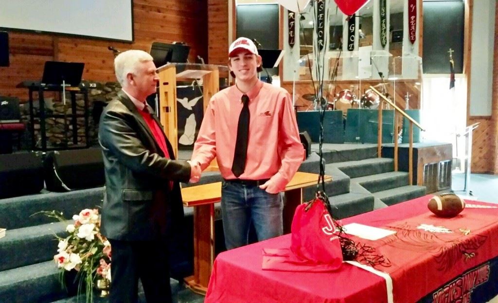 Jacksonville Christian quarterback Daylon Brackett is congratulated by Thunder coach Tommy Miller after signing a leadership scholarship to play football at Jacksonville State. (Photo by Joel Brackett)