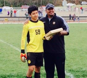 Oxford keeper Luis Jimenez (L) accepts the tournament's Defensive MVP award from Yellow Jackets coach Dwight McDonald Saturday.