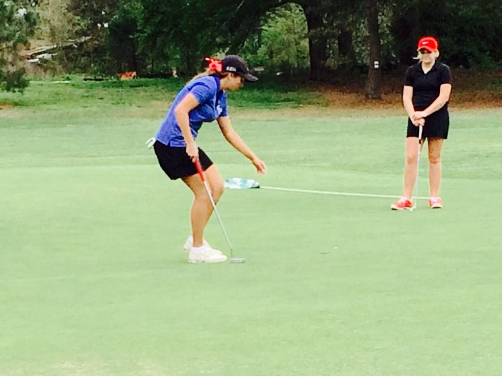 White Plains' Layne Dyar retrieves her ball from the cup on the eighth green after sinking her third birdie in a four-hole stretch Friday; JCA's Chloe Borders had a front-row seat. On the cover, Dyar discusses the day's round with her teammates.