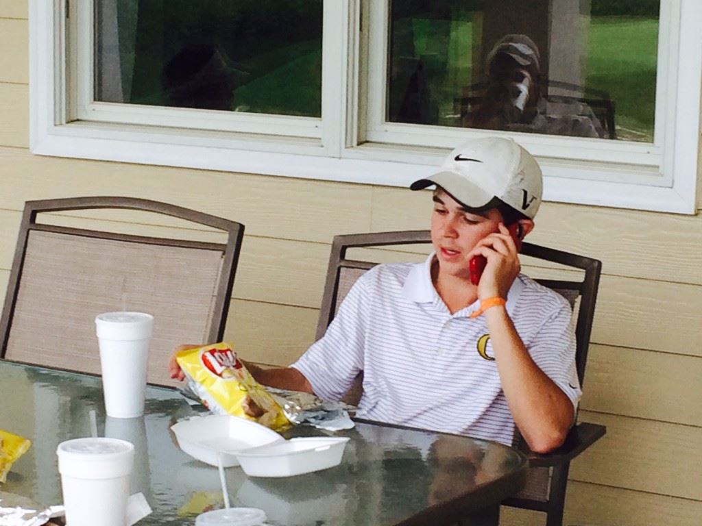 Oxford's Tyler Putnam takes in some lunch and a phone call after finishing second to help the Jackets qualify for the Class 6A substate tournament.