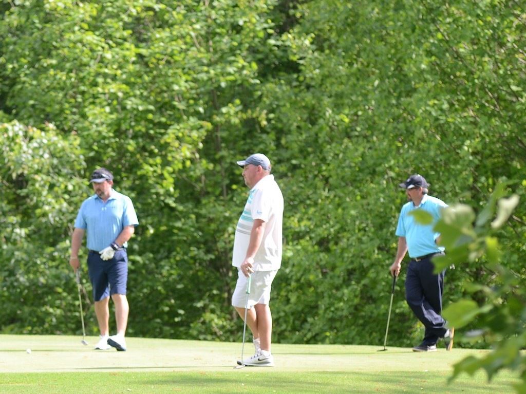 Flight winners Dan Griffin (L) and Jonathan Pate (R) and flight runner-up Adrian Geeting watch a putt roll on the 14th green Sunday.