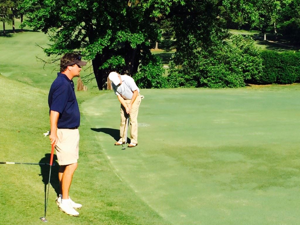 Brian Woodfin (L) stands by as partner Jake Spott rolls a birdie putt on the 16th green during Saturday's EA Sports Today Challenge Cup matches at Anniston Country Club. 