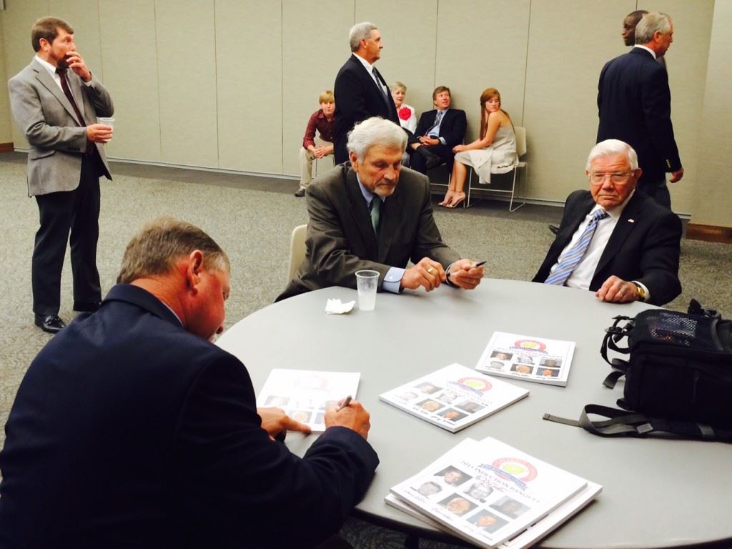 Calhoun County Sports Hall of Fame inductees (from left) Jerry Weems, Henry O'Steen and Don Salls autograph programs before the start of the formal enshrinement ceremonies.