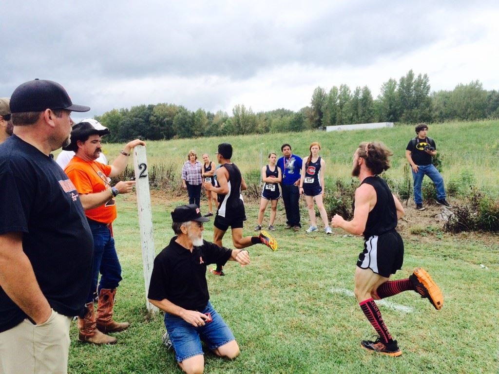 Lane Trapp's dad Shane (orange shirt) checks the time as Lane comes up on the two-mile marker in the Creekbank Invitational.