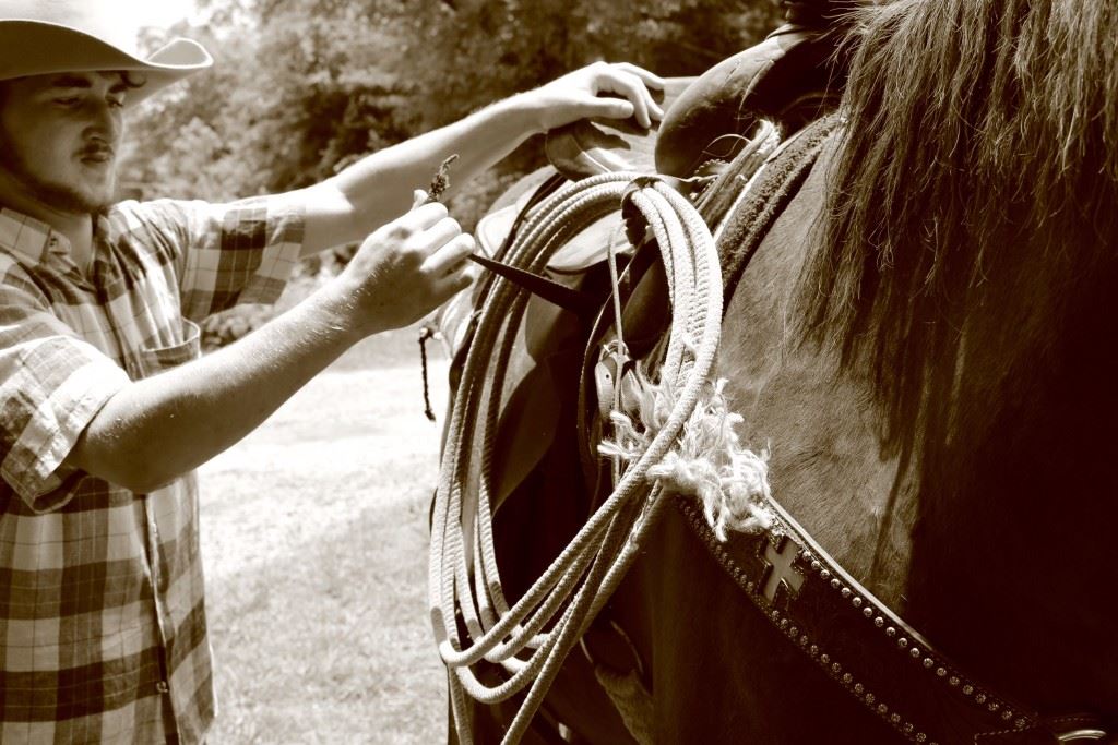 Lane Trapp gets his horse, Dynamite, ready for a ride.