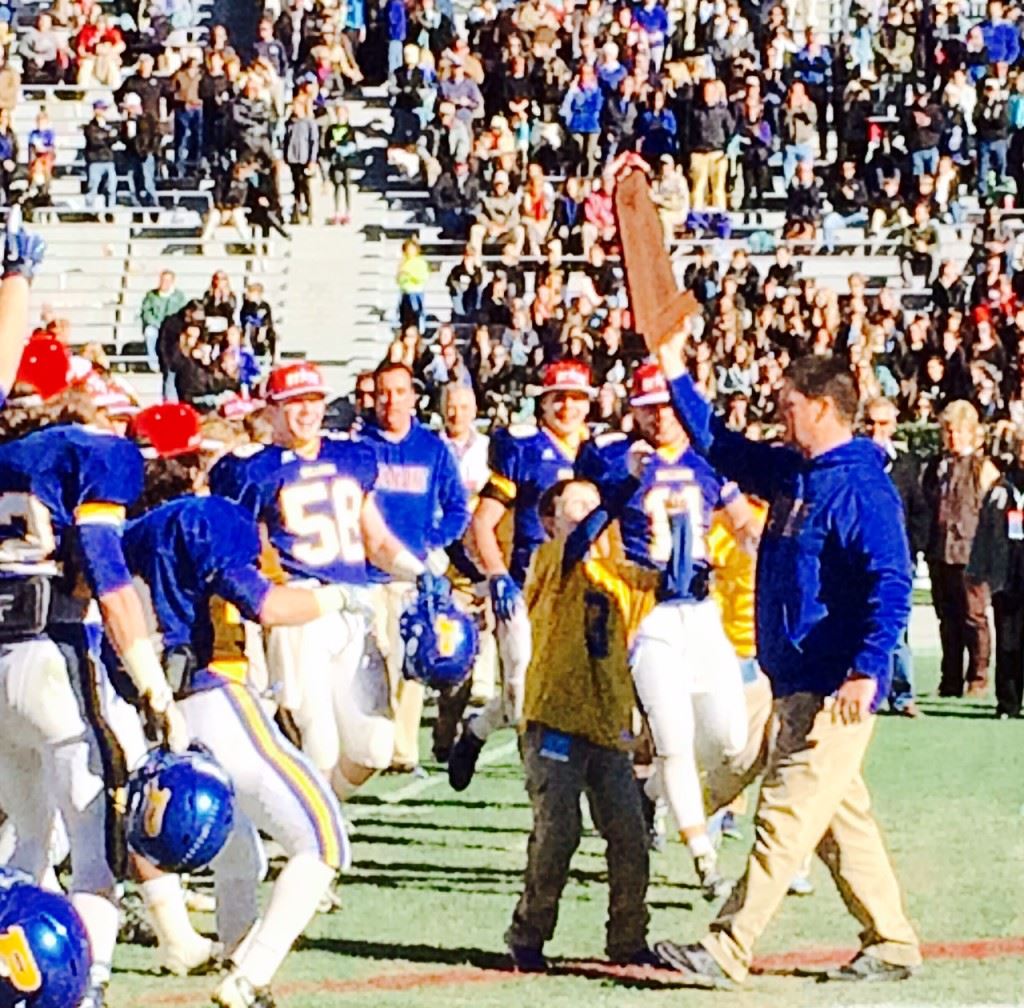 Piedmont coach Steve Smith carries the blue state championship trophy to his awaiting team.