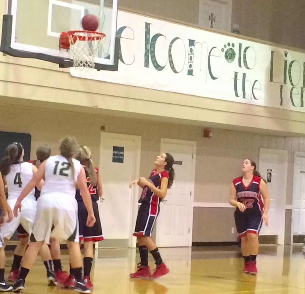 JCA and Faith Christian players stand poised to see if the ball will fall through the hoop or roll off the rim Monday night.