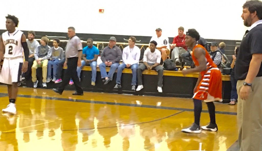 Alexandria's Jamal Tucker (C) stands poised between Lincoln coach Rush Rutledge (R) and Zay Caldwell to receive the ball in the second quarter Thursday. Jamal scored 12 second-quarter points after Luke Tucker (cover) scored the Cubs' first 10.