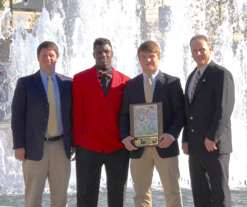 Piedmont quarterback Taylor Hayes (holding plaque) stands with (from left) Bulldogs head coach Steve Smith, 3A Lineman of the Year finalist Neonta Alexander and assistant coach James Blanchard after winning the Class 3A Back of the Year award Wednesday. (Photo by Shannon Fagan)