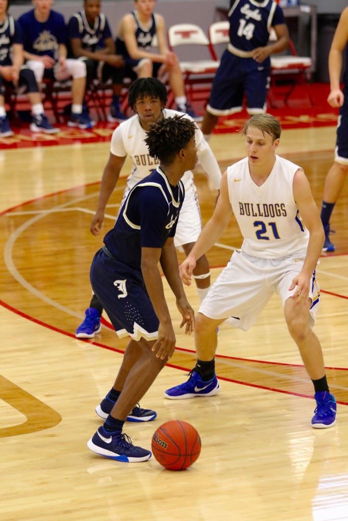 Piedmont's Bayley Blanchard (21) steps in front of Jacksonville's Cam Horton to prevent him from driving to the basket Monday. On the cover, Piedmont's Easton Kirk and Jacksonville's Taye Ackles dive for a loose ball. (Photos by Kristen Stringer/Krisp Picks Photography)