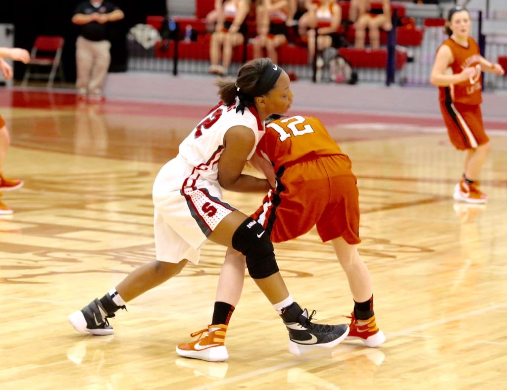 Saks' Maiya Northard (L) ties up her opposite number from Alexandria, Sarah Kilgore, during Thursday's game. On the cover, Saks coach Michelle Lively gives instruction in the huddle. (Photos by Kristen Stringer/Krisp Pics Photography)