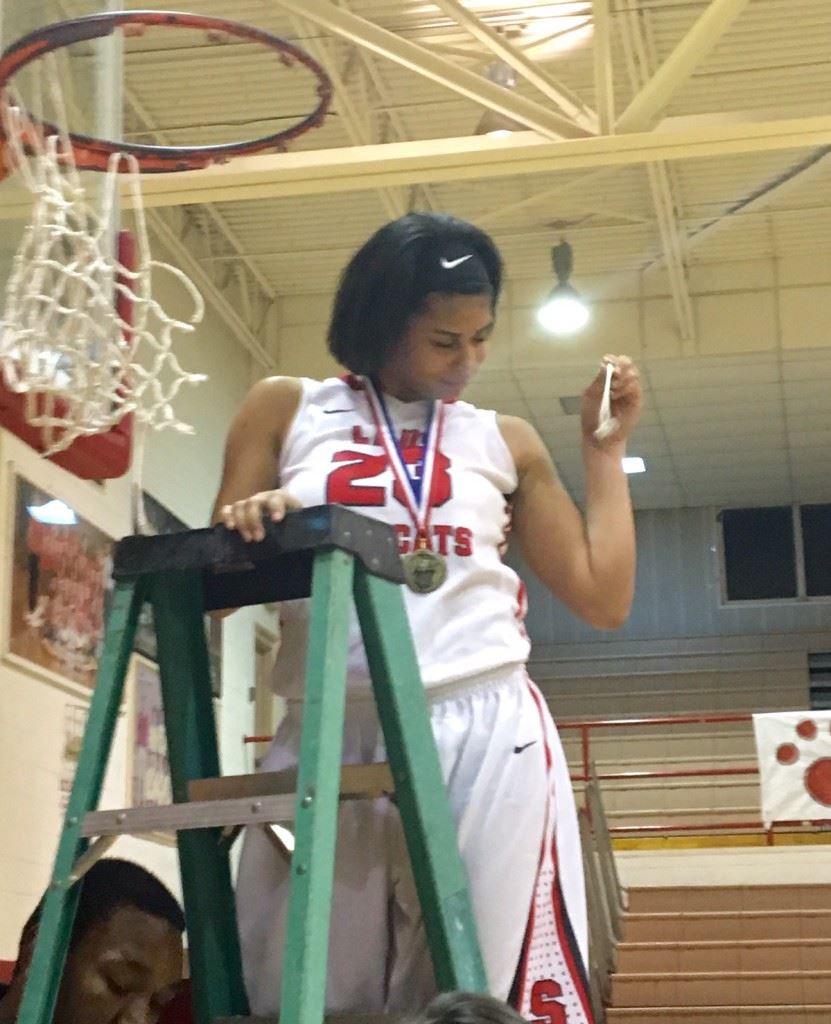 Nothing but net! BryAnna Browning gets her strand as the Saks girls basketball team takes turns cutting the net after winning the area championship Friday night. (Photo by Jason Katz)