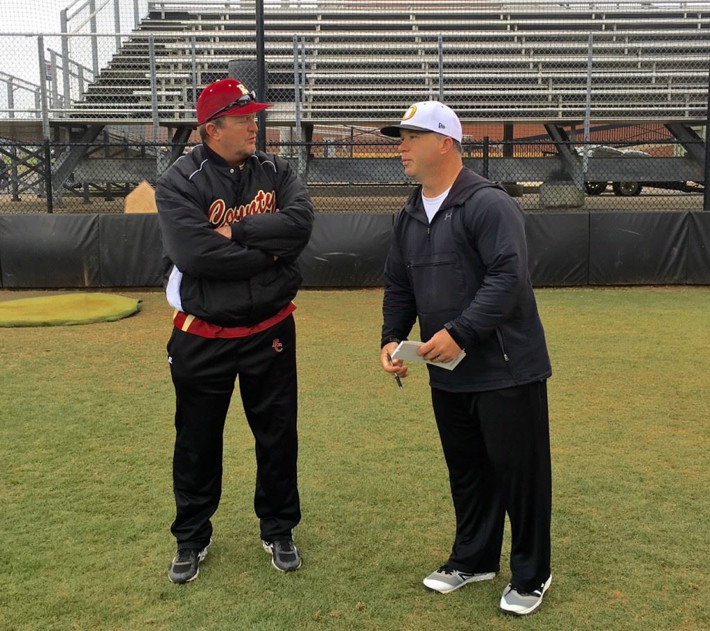 Oxford baseball coach Wes Brooks (R) talks with Russell County coach Tony Rasmus before the rain came in their Opening Day game Monday.