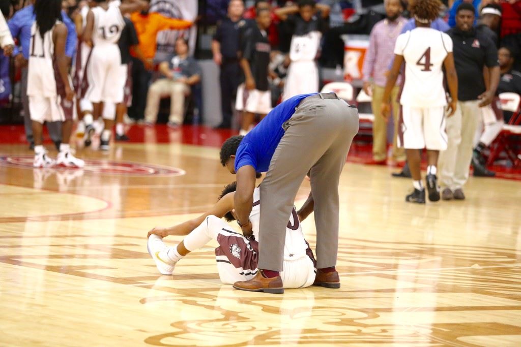 Anniston guard Tray Croft is consoled on the floor after his potential winning 3-pointer hit off the rim leaving the Bulldogs two points short of J.O. Johnson. Below, Croft looks to make a move on JOJ's Jarius Grayson. On the cover, the loss brought the end of coach Schuessler Ware's 19-year tenure. (Photos by Kristen Stringer/Krisp Pics Photography)