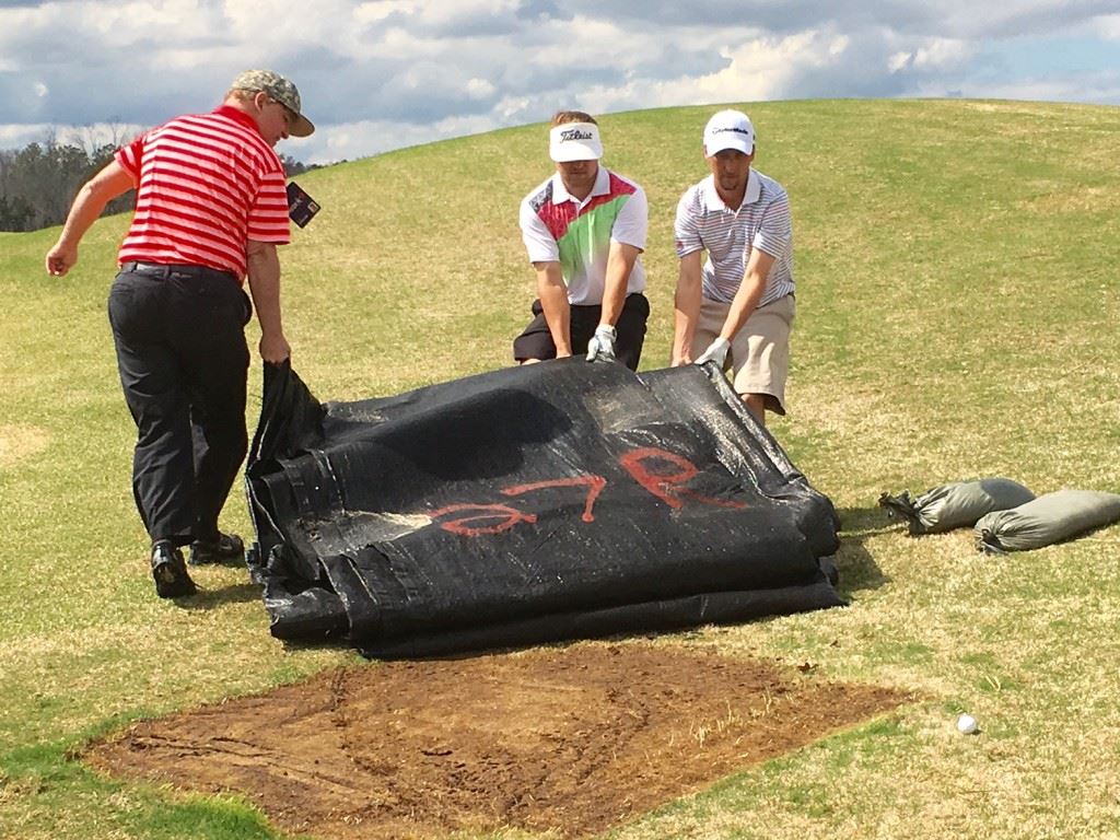 Eventual champions Caleb Bowen and Cory Etter get some help moving a loose impediment near the ninth green Sunday. On the cover, Bowen (R) and Etter point out their winning score.