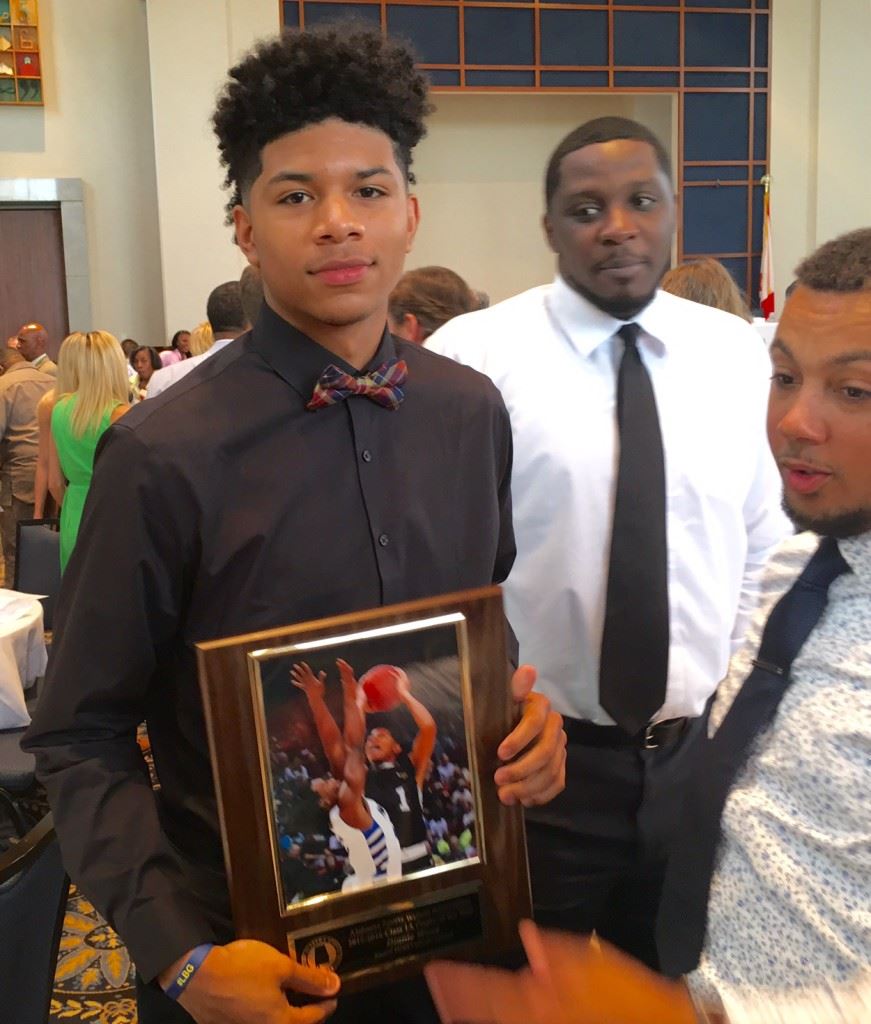 Sacred Heart sophomore Diante Wood displays his award for being named Alabama's Class 1A Boys Player of the Year. On the cover, 1A finalists Tykeah Rogers of Spring Garden (L) and Wood in action. (Cover photos by Kristen Stringer/Krisp Pics Photography)