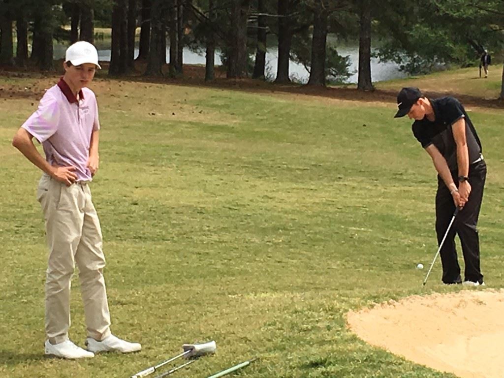 Donoho's Jacob Lecroy (L) waits patiently as White Plains' Layton Bussey chips over the greenside bunker on 18 for an eagle that gave him a 3-under-par 69 Friday.