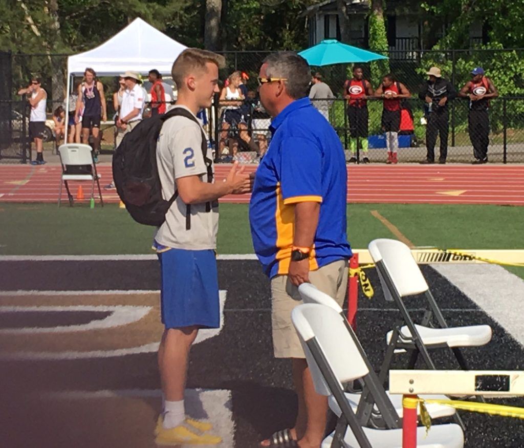 Piedmont pole vaulter Will Mitchell (L) and his dad, Bulldogs coach Mark Mitchell, talk about the day's jumps.