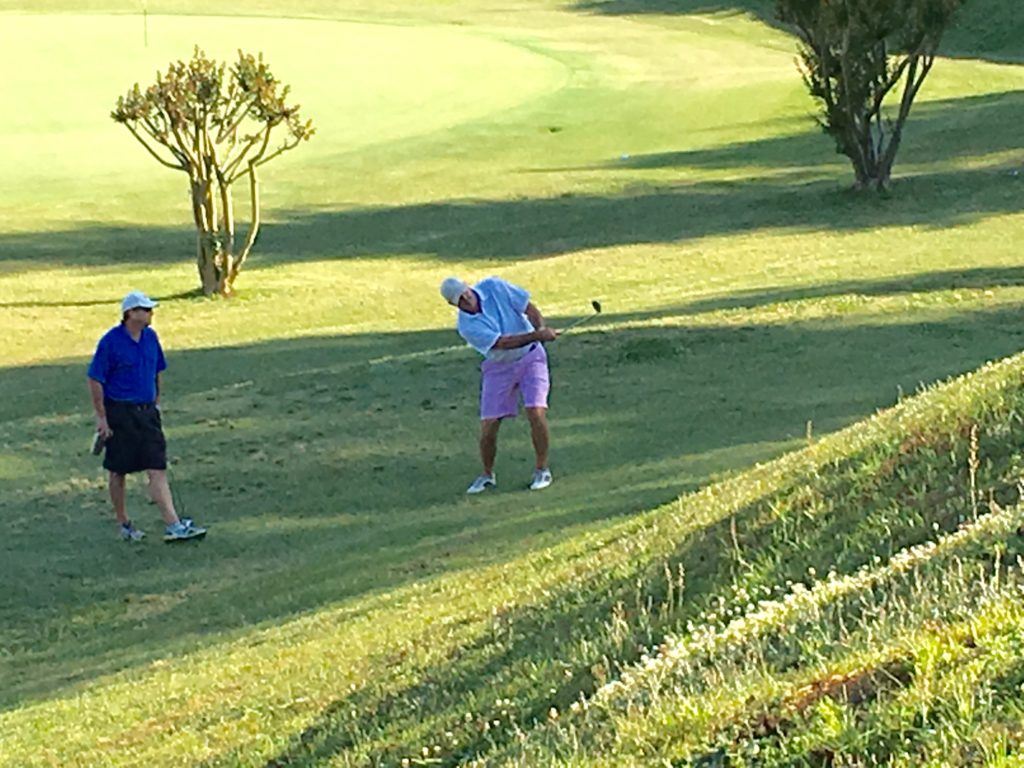 Gary Wigington tries to lift a shot from the bottom of the hill on the crucial 16th hole Sunday. On the cover, Freeman Fite holds the trophy after winning the Wilfred Galbraith Invitational for a record seventh time.