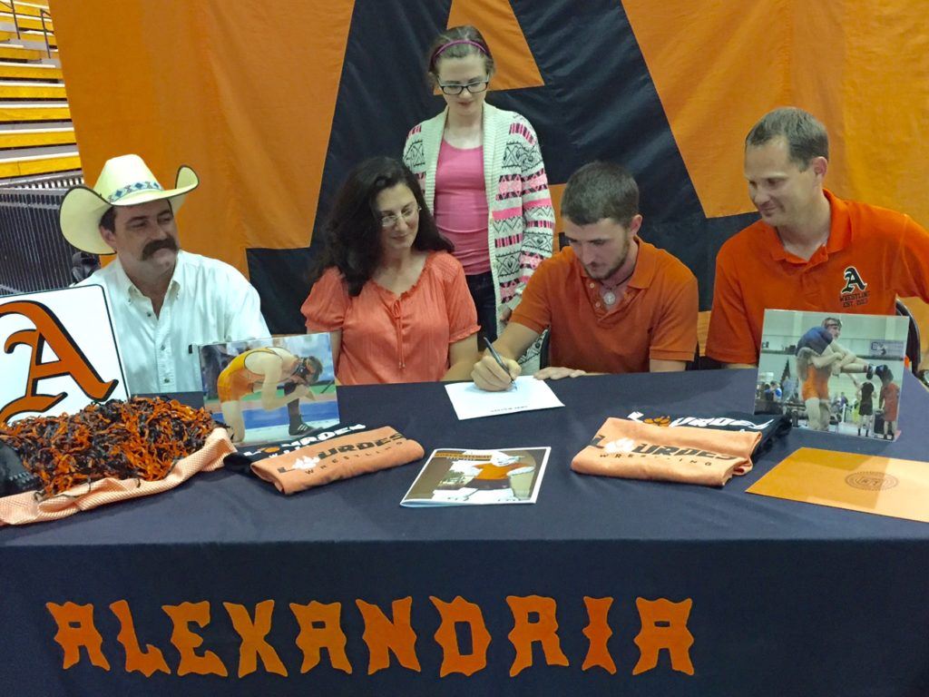 Alexandria senior Lane Trapp signs a wrestling scholarship with Lourdes University as his family and Valley Cubs coach Frank Hartzog look on.