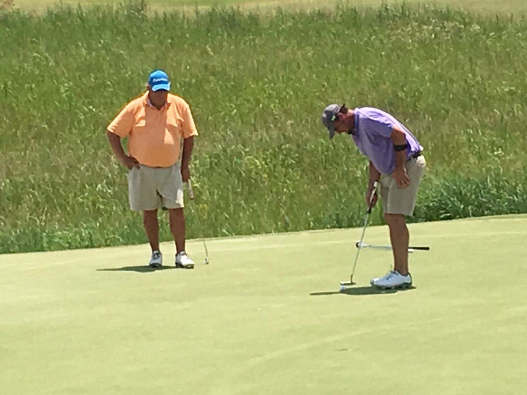 Chad Calvert (L) watches Chad Reavis putt on the 16th green during Saturday's first round of the Silver Lakes Championship.