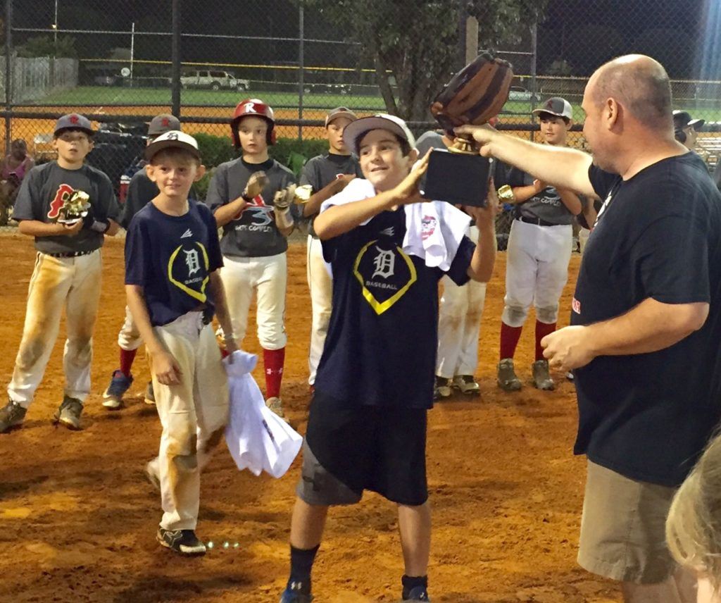 Honorary team member Caleb Watts, who recently lost his mother and grandmother in an auto accident, accepts the winner's trophy Sunday night after the East Alabama Dynasty won the BPA 12U World Series. (Special photo)