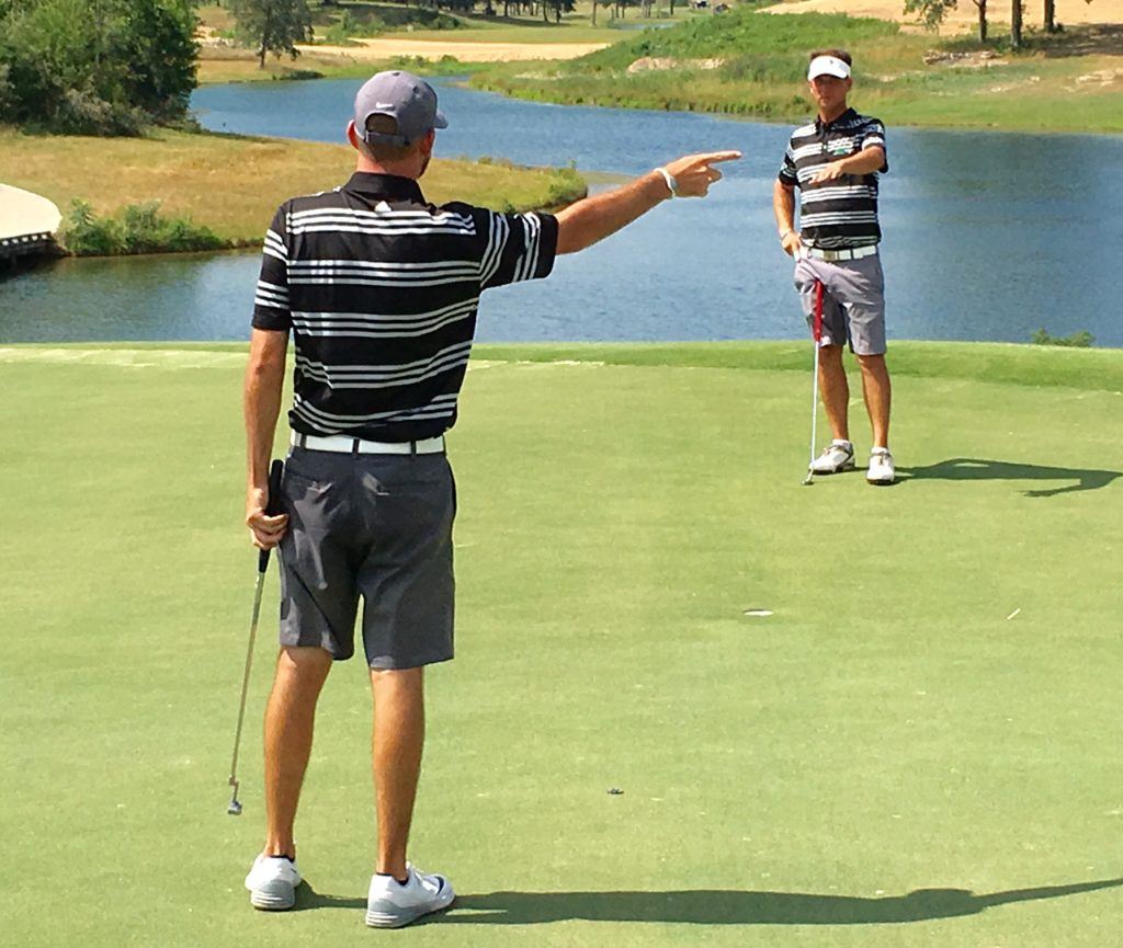 Brennan Clay and Jeremy McGatha (R) try to help each other read a birdie putt on Mindbreaker 9 Friday. They made it to turn in 8-under.