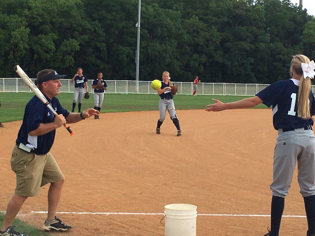 Pleasant Valley coach David Bryant hits grounders to his North infielders before Tuesday's all-star doubleheader. On the cover, Alexandria's Timberlyn Shurbutt (R) and Cleburne County's Kiara Akles, the North MVP, await their turn.