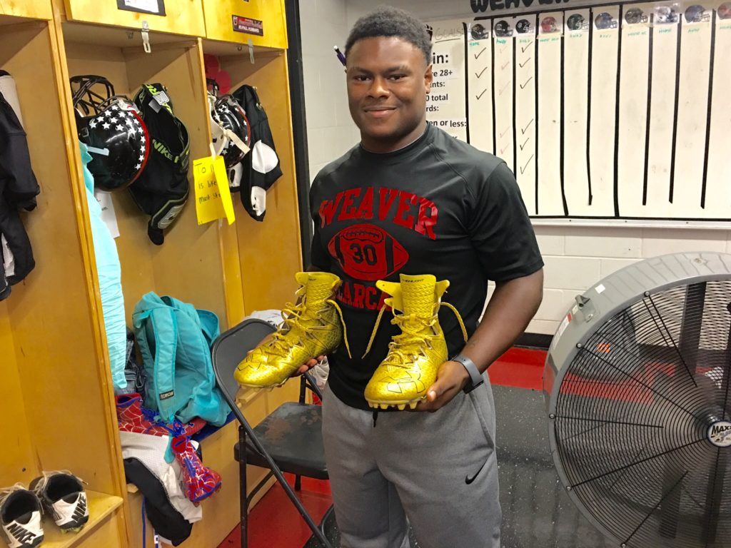 Weaver fullback Tyrik Hall shows off the gold cleats he's been playing in this season. Teammate Maurice Goodman's Spider-Man cleats can be seen in the lower left corner.