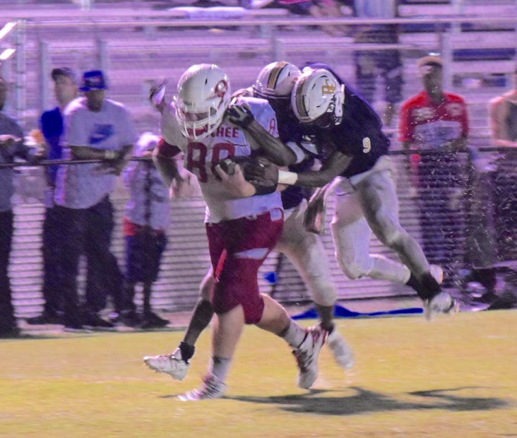 Ohatchee's C.J. Ray hauls in a pass with two Randolph County defenders hanging on him. On the cover, a Randolph County player plays on through the rain. (All photos by Jeremy Wortham/Tiger Den Photography)