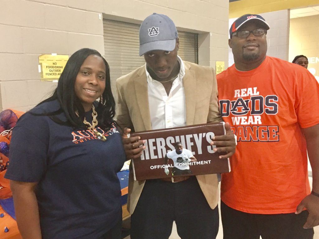 Oxford linebacker K.J. Britt stands with his parents holding the big chocolate bar he used to make his commitment to Auburn Monday.